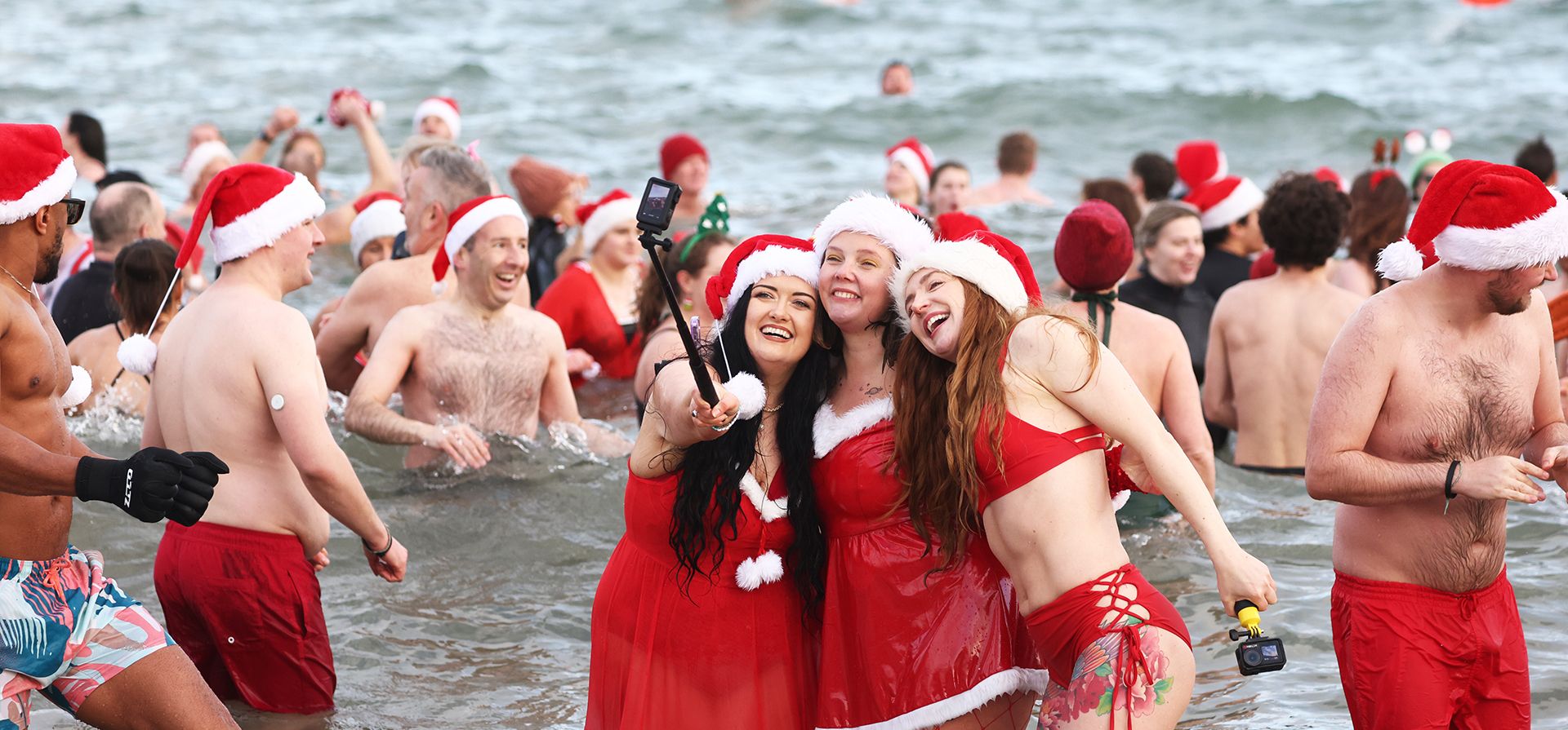 La gente se lanza al mar en la bahía de Helen, Irlanda del Norte, para el baño anual de Nochebuena en las frías aguas del lago Belfast Lough para recaudar fondos para Dementia NI y Air Ambulance NI, el miércoles 24 de diciembre de 2025. (Foto AP/Peter Morrison)