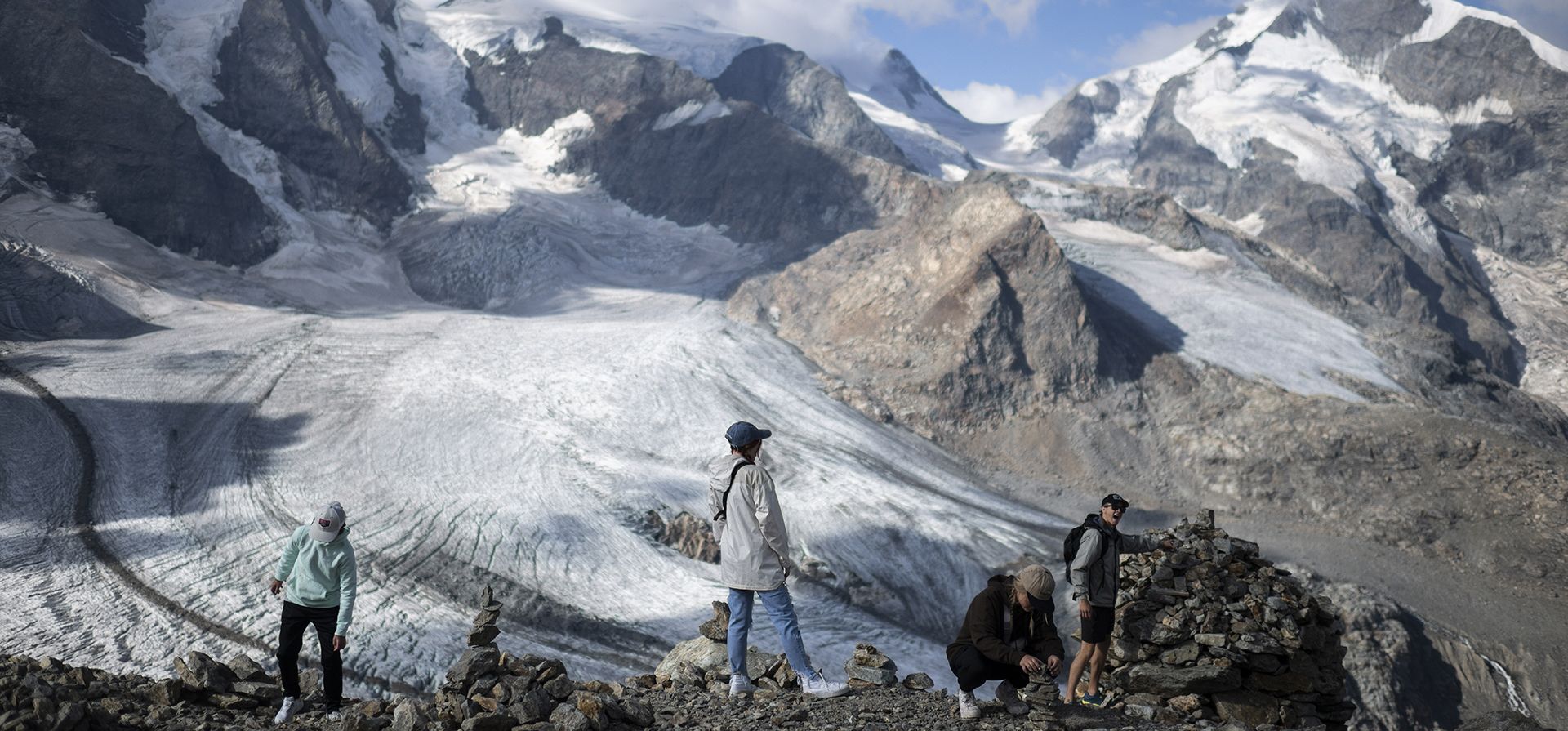 La gente permanece frente al grupo montañoso Bernina con los glaciares Pers y Morteratsch en Pontresina, Suiza, el miércoles 10 de agosto de 2022.
