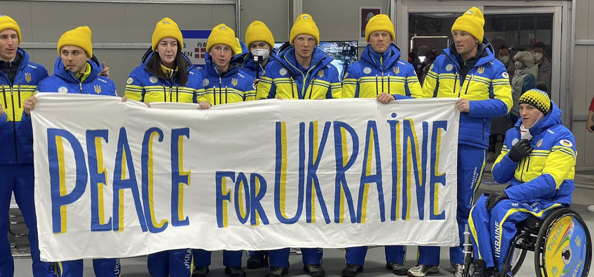 Miembros de la delegación del Comité Paralímpico Nacional de Ucrania sostienen un cartel antes de laa ceremonia de apertura de los Juegos Paralímpicos de Invierno de Beijing 2022 en Beijing, China, el viernes 4 de marzo de 2022.