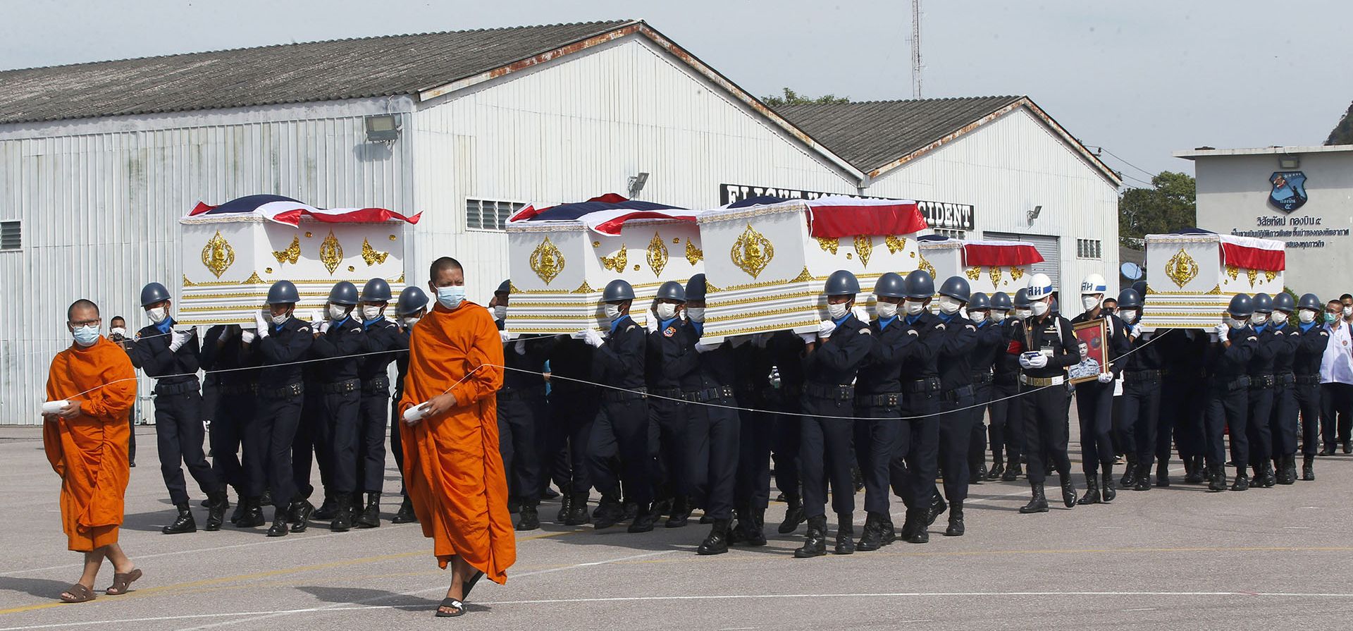 Monjes budistas tailandeses caminan frente a los ataúdes de las víctimas del hundimiento del domingo por la noche de un buque de guerra de la Armada tailandesa mientras eran transportados en una ceremonia de repatriación con ritos religiosos en la provincia de Prachuap Khiri Khan, Tailandia, el jueves 22 de diciembre de 2022. (Foto AP/Anuthep Cheysakron)