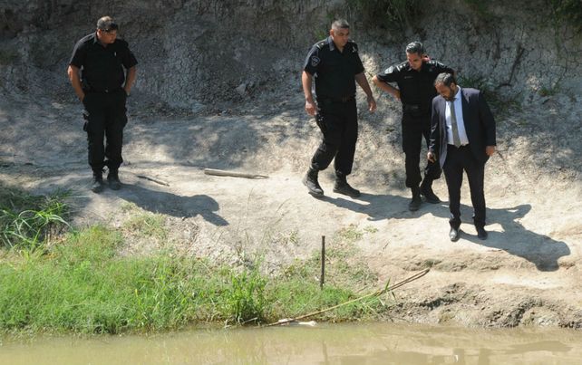 El fiscal Adri&aacute;n Spelta contempla el miembro inferior hallado en el agua. (Foto: Celina Mutti Lovera)