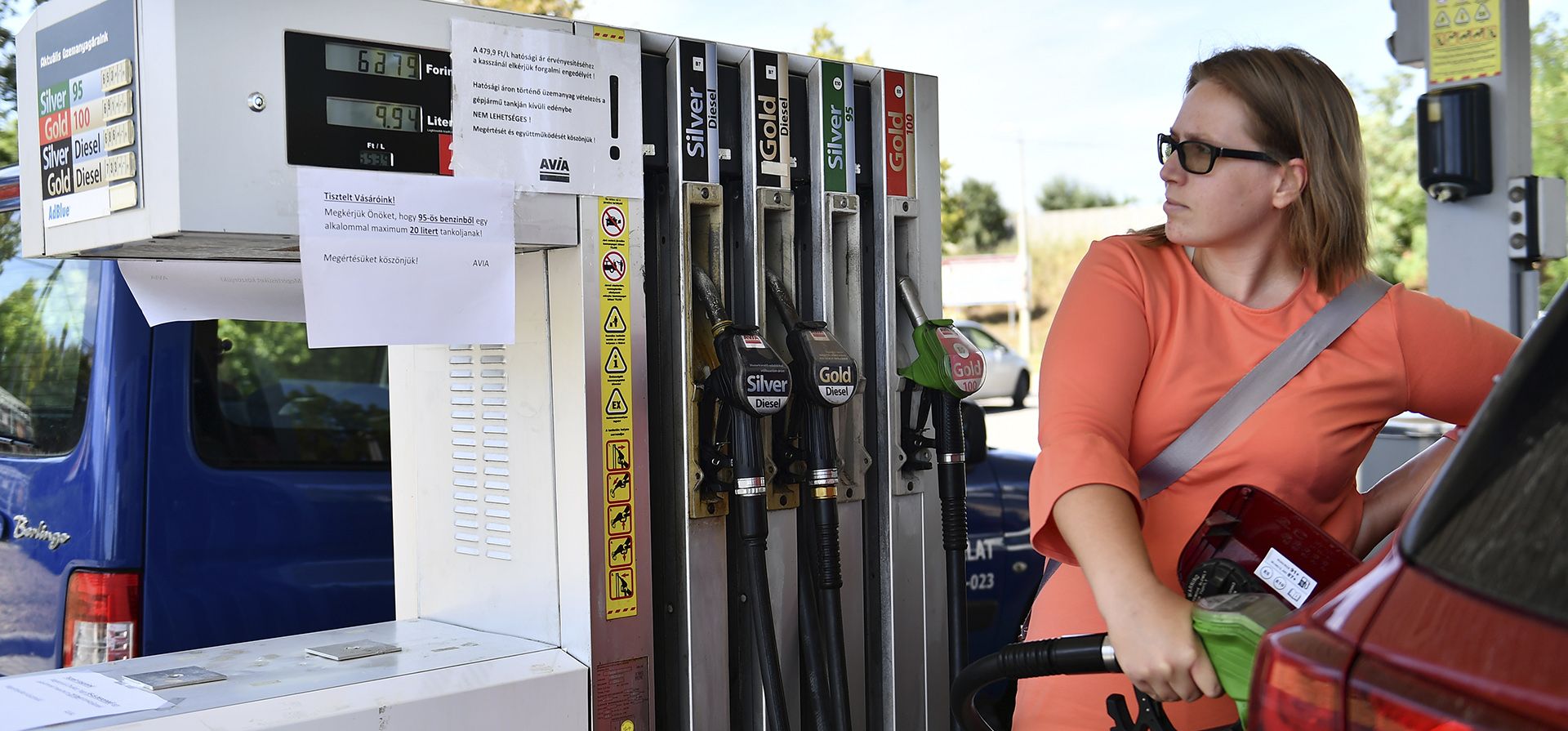 Una automovilista húngara carga combustible mientras lee la pancarta que dice