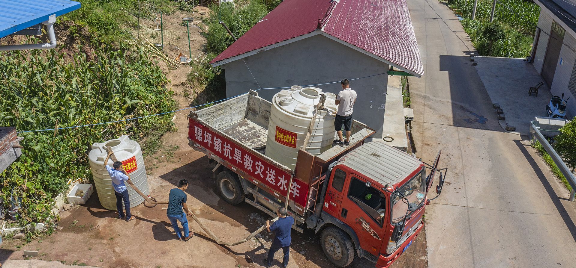 Trabajadores transfieren agua de un camión cisterna a los residentes de la aldea de Luoping del condado de Wushan, en Chongqing, suroeste de China, el martes 16 de agosto de 2022. Temperaturas inusualmente altas y una sequía prolongada están afectando grandes franjas de China.