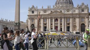 Peregrinos, uno de ellos con una cruz en la mano, caminan por la Plaza de San Pedro del Vaticano después de que el cardenal camarlengo Kevin Joseph Farrell anunciara el fallecimiento del papa Francisco, el lunes 21 de abril de 2025. (Foto AP/Alessandra Tarantino)
