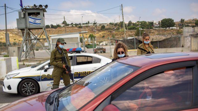 Soldados israelíes comprueban la identificación de una mujer palestina en el puesto de control del cruce de Tapuach junto a la ciudad de Naplusa en Cisjordania.