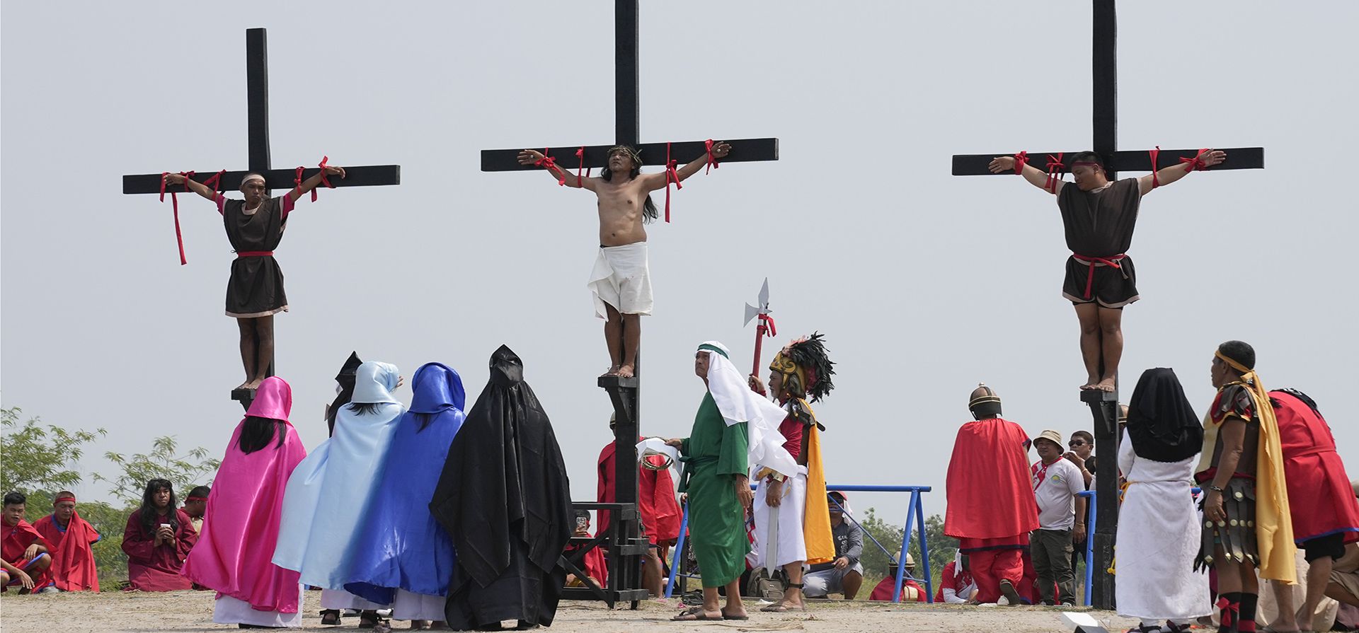 Rubén Enaje, centro, permanece en la cruz junto a otros dos devotos durante una recreación de los sufrimientos de Jesucristo como parte de los rituales del Viernes Santo el 7 de abril de 2023 en el pueblo de San Pedro, Cutud, provincia de Pampanga, al norte de Filipinas. (AP Photo/Aaron Favila)