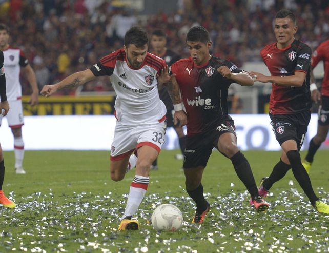 La pelea. Nacho Scocco intenta maniobrar ante la marca mexicana. Newells fue superado por Atlas en Guadalajara.
