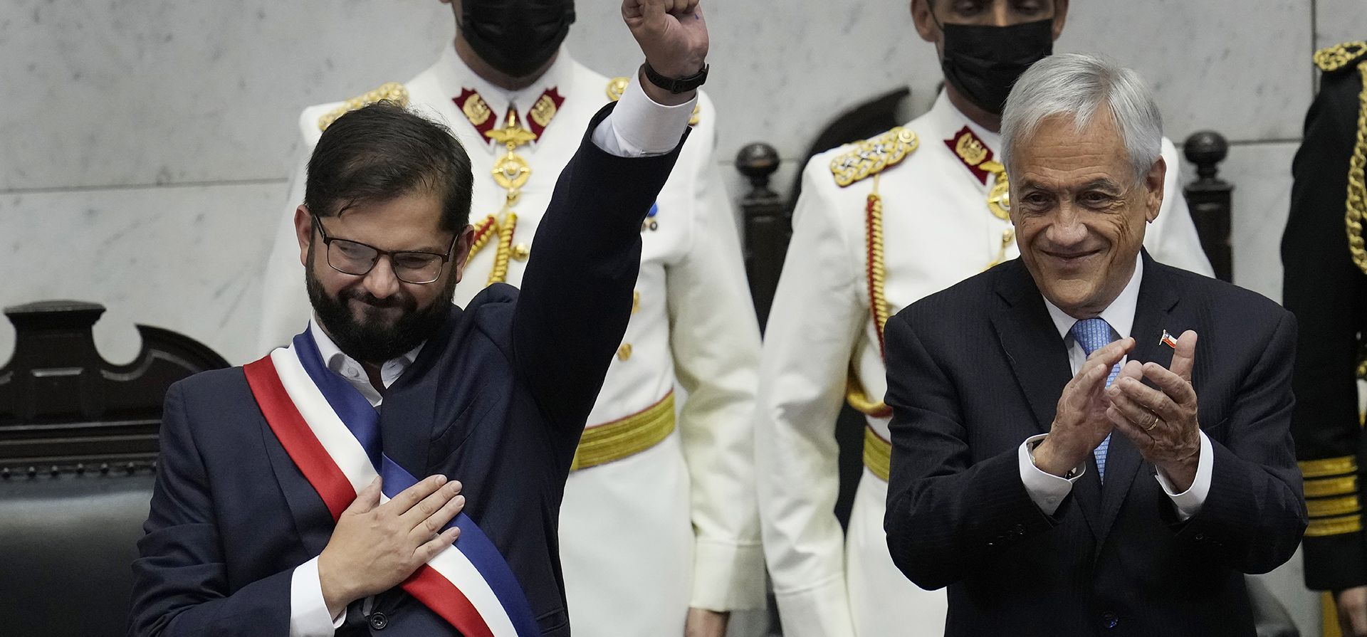 El nuevo presidente de Chile, Gabriel Boric, a la izquierda, levanta el puño mientras el presidente saliente, Sebastián Piñera, aplaude durante la ceremonia de juramentación de Boric en el Congreso en Valparaíso, Chile, el viernes 11 de marzo de 2022. (Foto AP/Esteban Felix)
