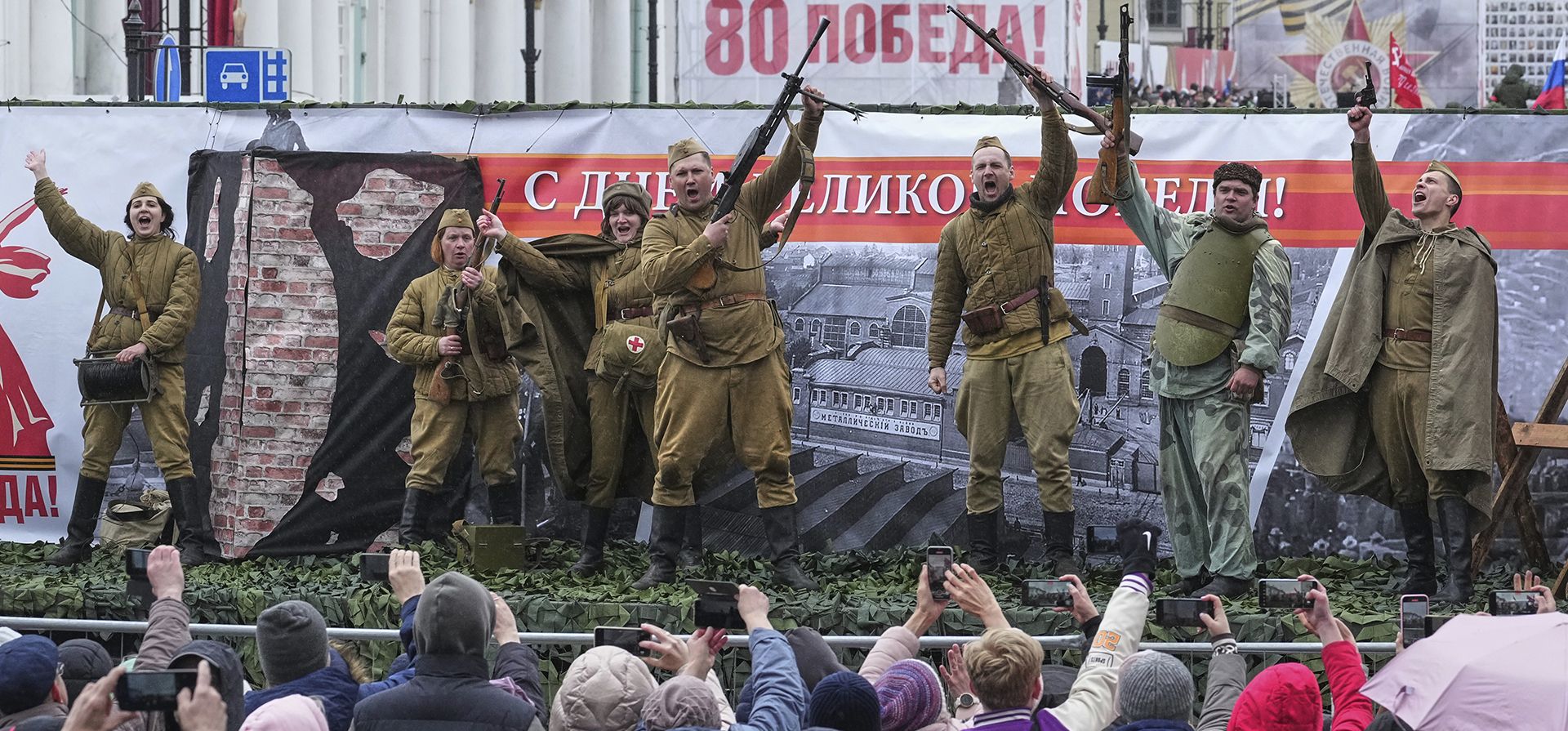 La gente mira a través de una valla a los actores, vestidos con uniformes del ejército soviético, que viajan en una plataforma móvil durante un ensayo general para el desfile militar del Día de la Victoria en la plaza Dvortsovaya (Palacio) de San Petersburgo, Rusia, el miércoles 7 de mayo de 2025. (Foto AP/Dmitri Lovetsky) La gente mira a través de una valla a los actores, vestidos con uniformes del ejército soviético, que viajan en una plataforma móvil durante un ensayo general para el desfile militar del Día de la Victoria en la plaza Dvortsovaya (Palacio) de San Petersburgo, Rusia, el miércoles 7 de mayo de 2025. (Foto AP/Dmitri Lovetsky)