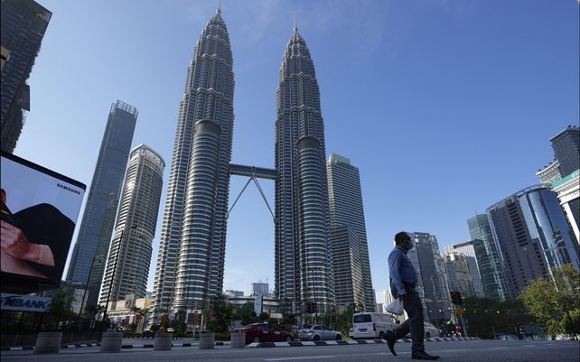 Un transeúnte camina por una calle vacía frente a las Torres Gemelas durante el primer día de la Orden de Control de Movimiento Total (MCO) en Kuala Lumpur