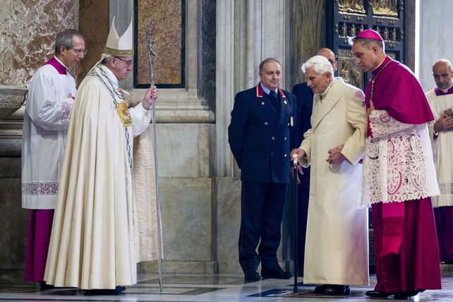 El Papa Francisco observa a Benedicto XVI en el ingreso a la basílica de San Pedro acompañado por monseñor Georg Gaenswein. 