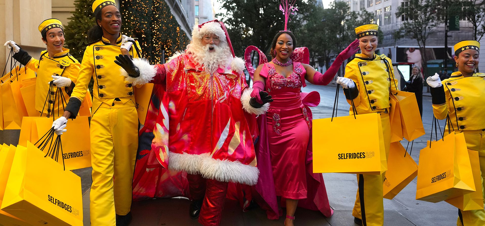 Un Papá Noel, una corista y unos botones posan frente a los escaparates navideños de Selfridges durante una presentación para los medios en Londres, el jueves 22 de octubre de 2026. (Foto AP/Kin Cheung)