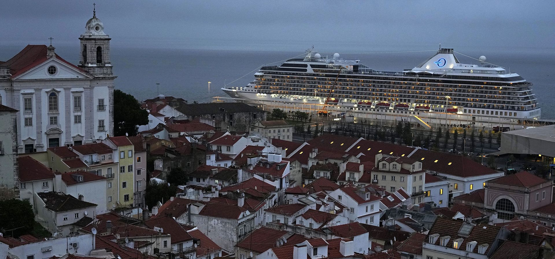 El crucero MS Marina atraca en el antiguo barrio de Alfama de Lisboa, en primer plano, al amanecer del martes 11 de octubre de 2022.