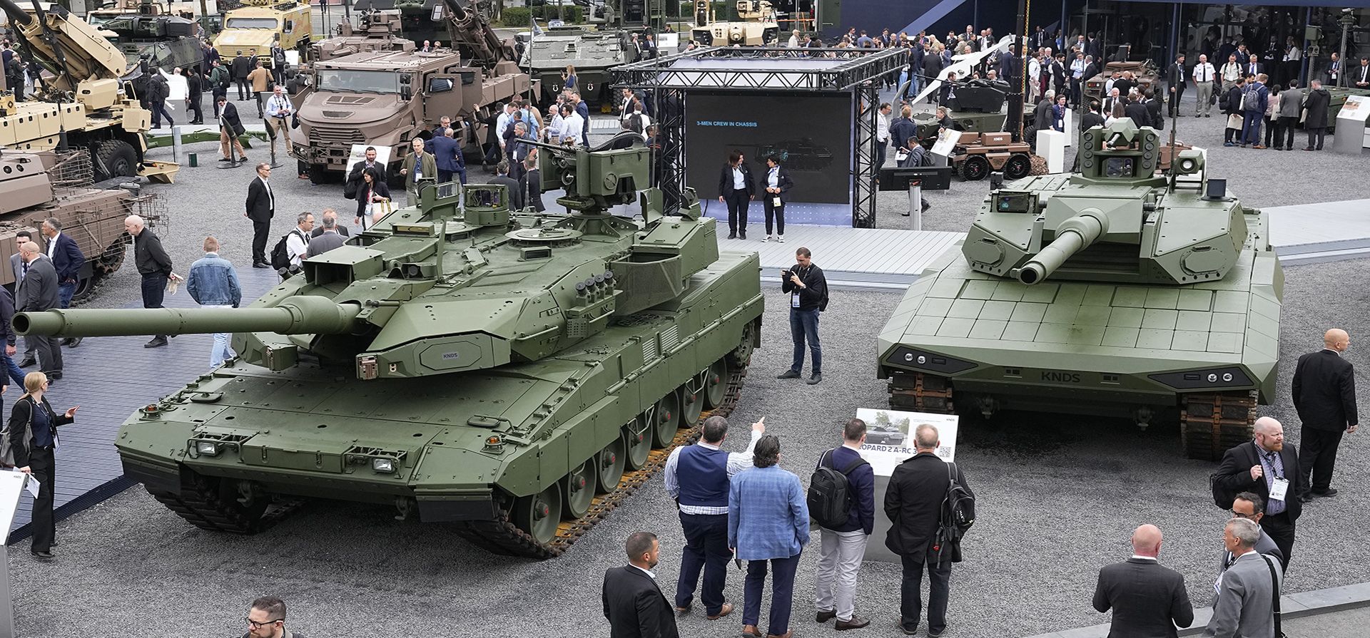 Visitantes se reúnen junto a un tanque Leopard 2 A8, izquierda, y un tanque Leopard 2A-RC-3.0 en la exposición Eurosatory Defensa y Seguridad, el miércoles 19 de junio de 2024 en Villepinte, al norte de París. (Foto AP/Michel Euler)