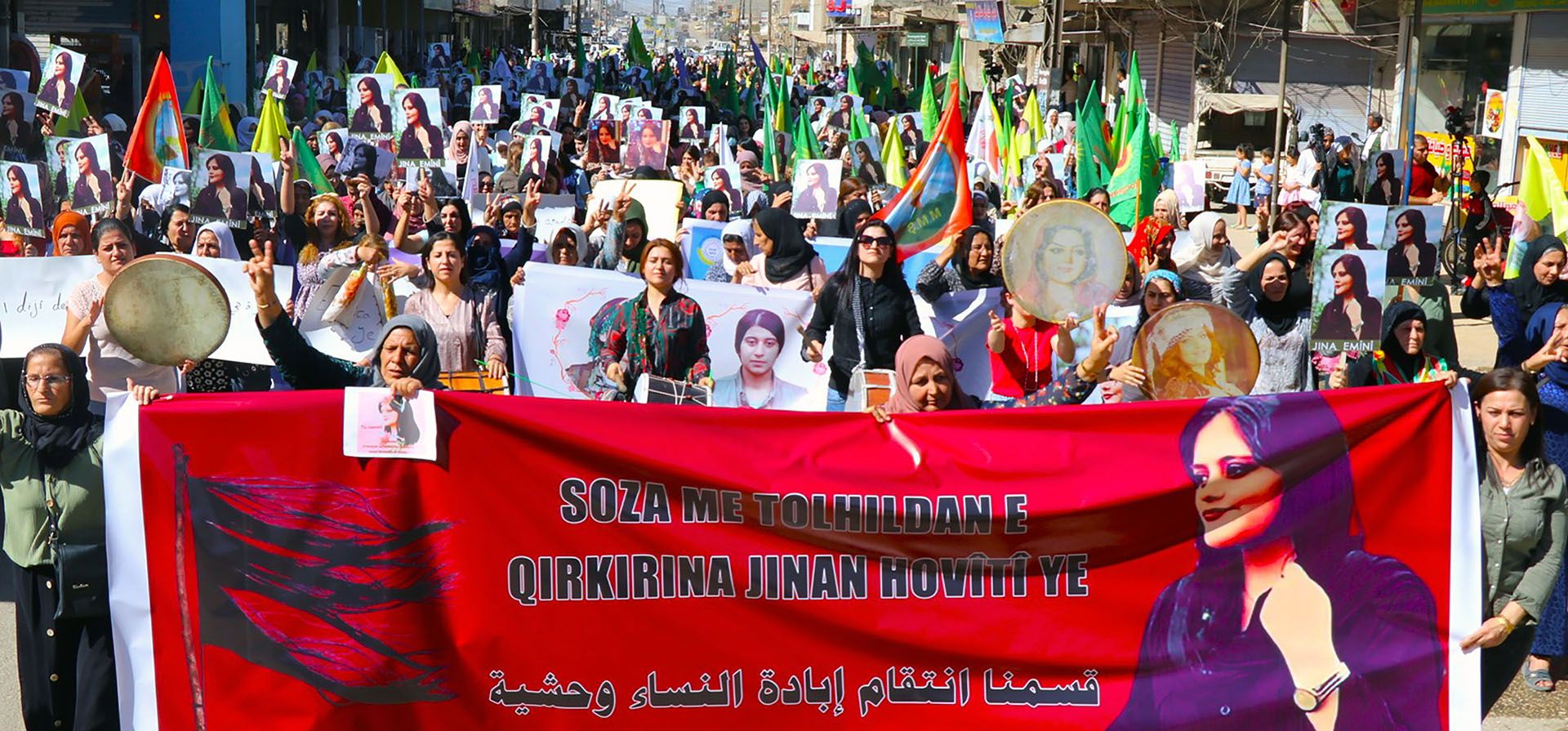 Mujeres kurdas sostienen una pancarta y retratos de la iraní Mahsa Amini durante una protesta que condena su muerte en Irán, en la ciudad de Qamishli, en el norte de Siria, el martes 27 de septiembre de 2022.