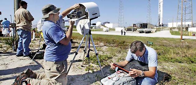 Los reporteros preparan las cámaras operadas por control remoto aguardando el lanzamiento de hoy.
