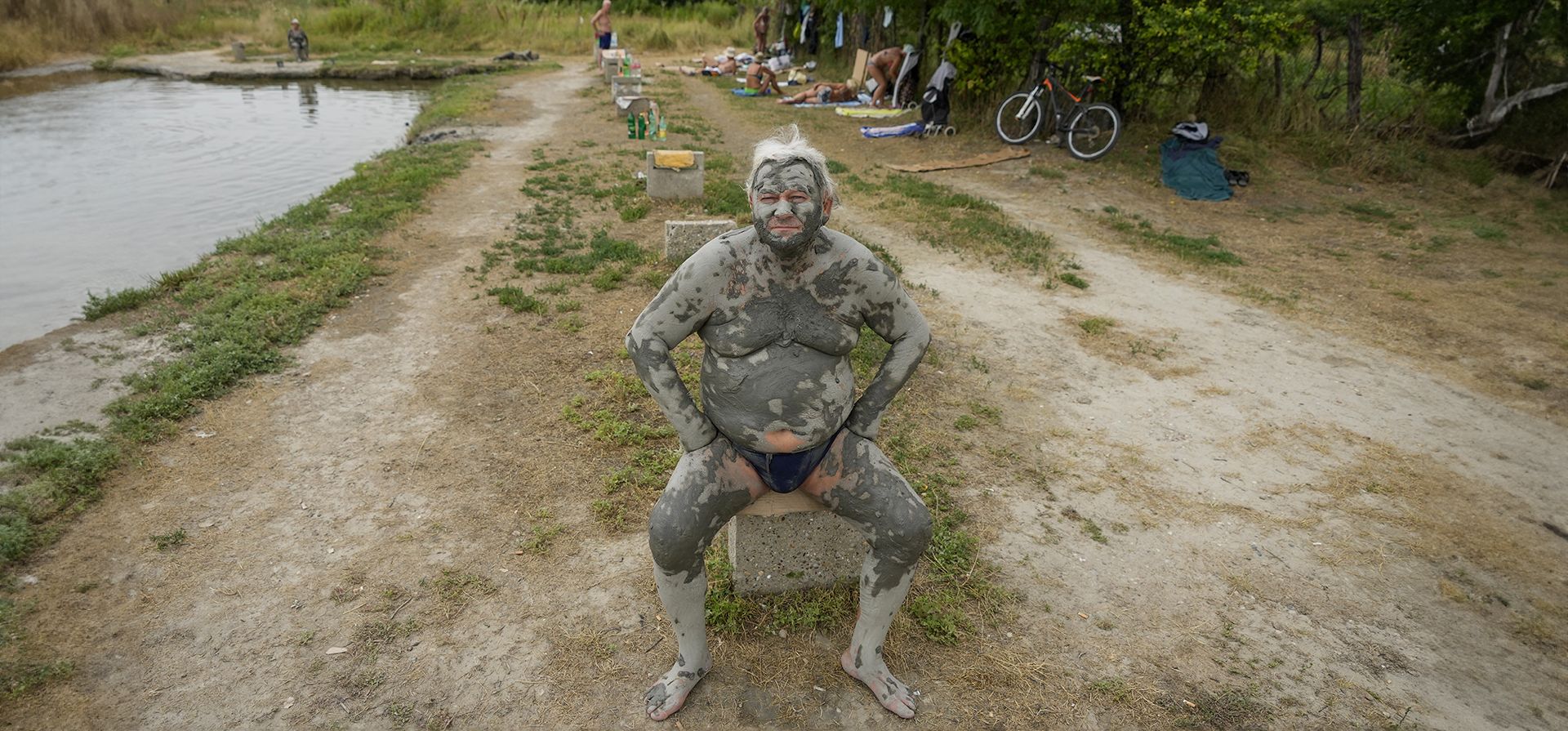 Un hombre cubierto de lodo toma el sol junto a una pequeña piscina de agua mineral en Ovca, un suburbio rural de Belgrado, Serbia, el martes 25 de julio de 2023. (Foto AP/Darko Vojinovic) Un hombre cubierto de lodo toma el sol junto a una pequeña piscina de agua mineral en Ovca, un suburbio rural de Belgrado, Serbia, el martes 25 de julio de 2023. (Foto AP/Darko Vojinovic)