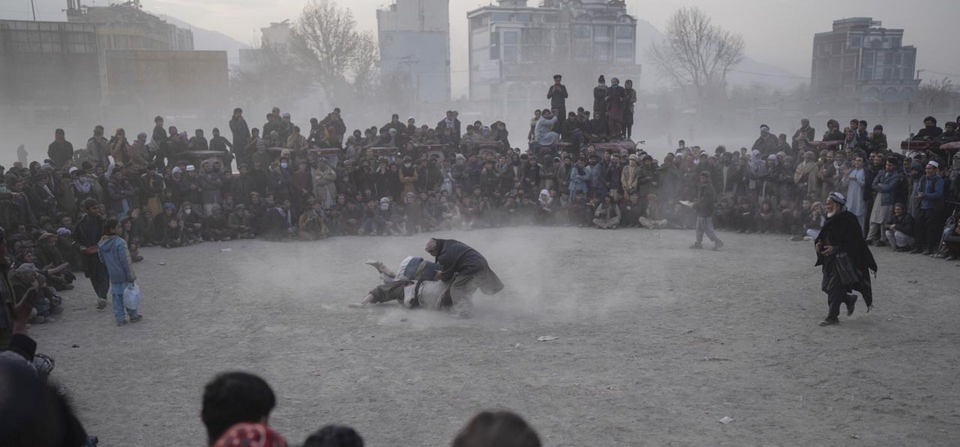 Hombres afganos luchan mientras los espectadores miran en Kabul, Afganistán. La escena se desarrolla cada semana después de las oraciones del viernes en el extenso parque Chaman-e-Huzori en el centro de Kabul, donde hombres, principalmente del norte de Afganistán provincias, se reúnen para mirar y competir en pahlawani, una forma tradicional de lucha libre.