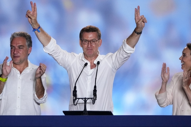 Alberto N&uacute;&ntilde;ez Feij&oacute;o celebra con gesto serio desde el hist&oacute;rico balc&oacute;n de la sede del PP en Madrid.