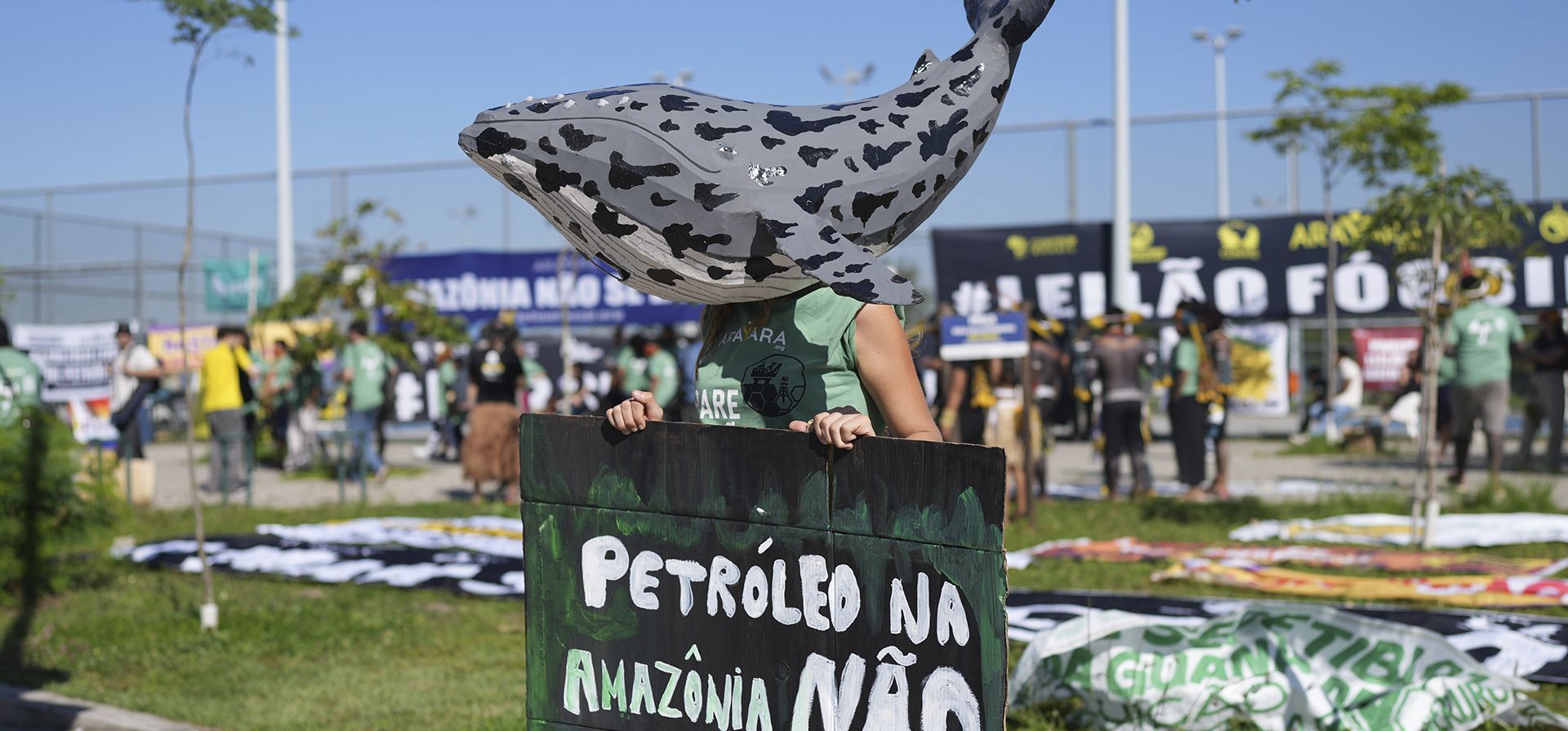 Un manifestante con una máscara de ballena sostiene un cartel en portugués que dice Un manifestante con una máscara de ballena sostiene un cartel en portugués que dice