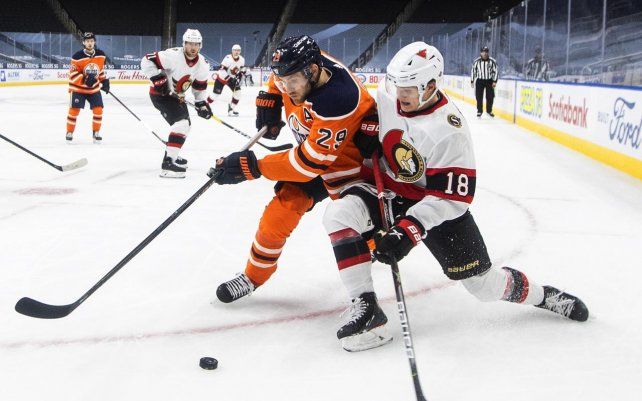 Leon Draisaitl de Edmonton Oilers y Tim Stuetzle de Ottawa Senators luchan por el disco durante el tercer período de un juego de hockey de la NHL, en Edmonton, Alberta, Canadá.
