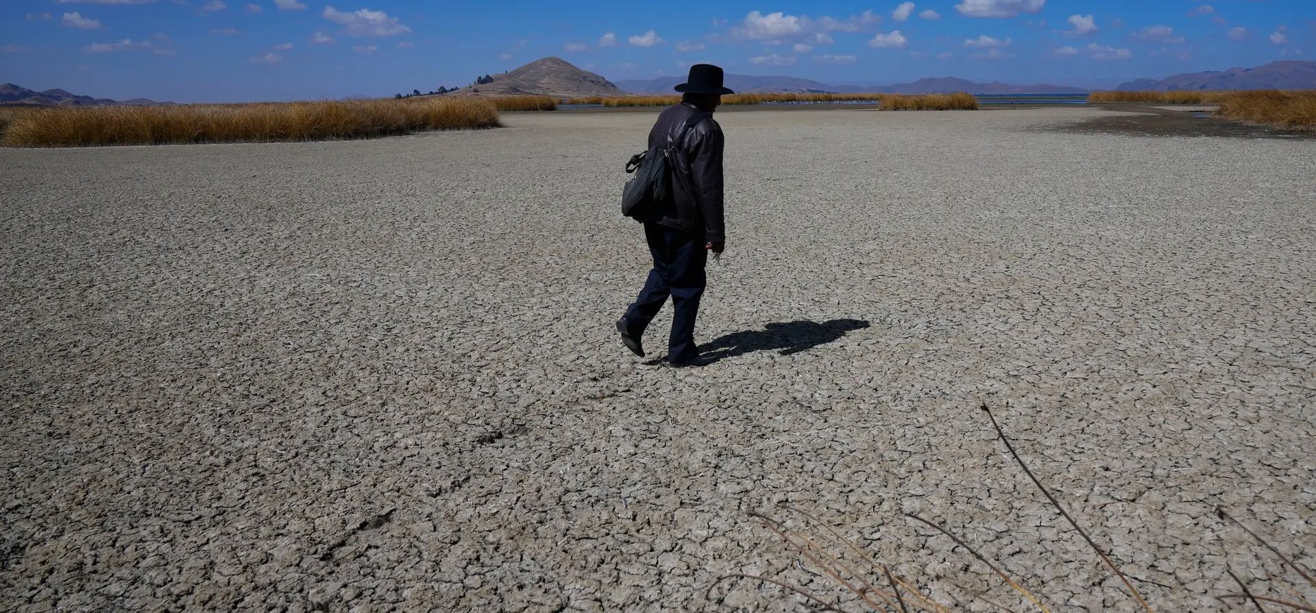 Huarina, Bolivia. Un hombre camina sobre el lecho seco y agrietado del lago Titicaca, donde el bajo nivel del agua está afectando a la flora y la fauna, así como a las comunidades que dependen de ella para su sustento. Fotografía: Juan Karita/AP Huarina, Bolivia. Un hombre camina sobre el lecho seco y agrietado del lago Titicaca, donde el bajo nivel del agua está afectando a la flora y la fauna, así como a las comunidades que dependen de ella para su sustento. Fotografía: Juan Karita/AP