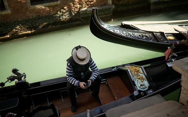 Un gondolero mira su teléfono mientras espera clientes. El período del Carnaval en Venecia generalmente marca el inicio de la temporada alta en una de las ciudades más visitadas del mundo