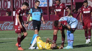Candia ya sufrió el esguince de rodilla y es auxiliado por el árbitro y varios jugadores de Lanús.