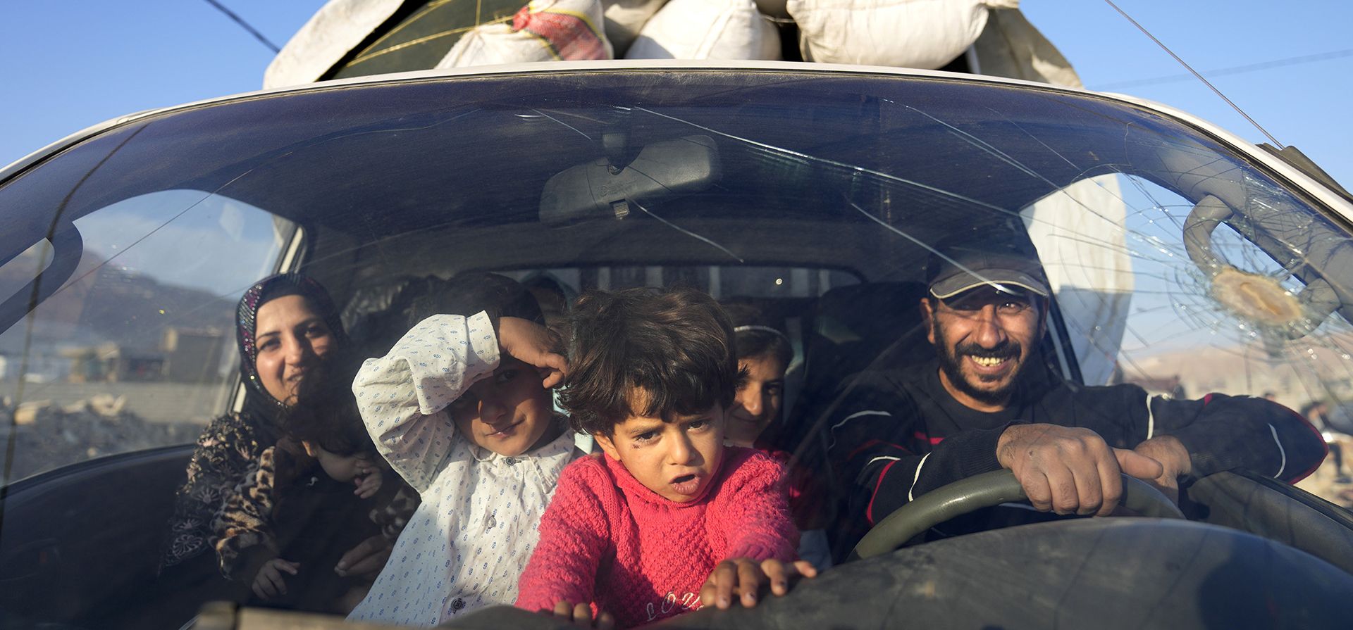 Una familia de refugiados sirios se desplazan en una camioneta, mientras esperan en un punto de reunión para cruzar la frontera de regreso a Siria, en la ciudad fronteriza libanesa oriental de Arsal, Líbano, el miércoles 26 de octubre de 2022.