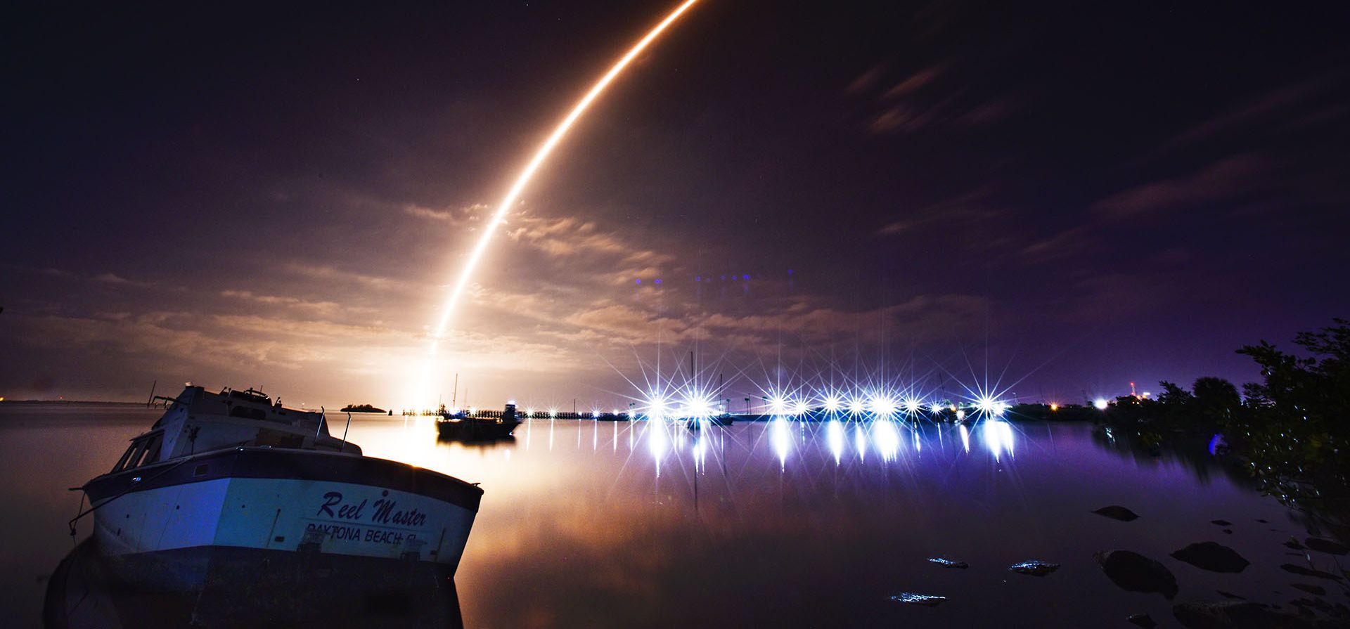 Con un barco abandonado y las luces de Canaveral Lock en primer plano, una imagen de larga exposición del lanzamiento del cohete SpaceX Falcon 9 desde la Plataforma 39-A en el Centro Espacial Kennedy la mañana del jueves 2 de febrero de 2023. (Malcolm Dinamarca/Florida Today vía AP)