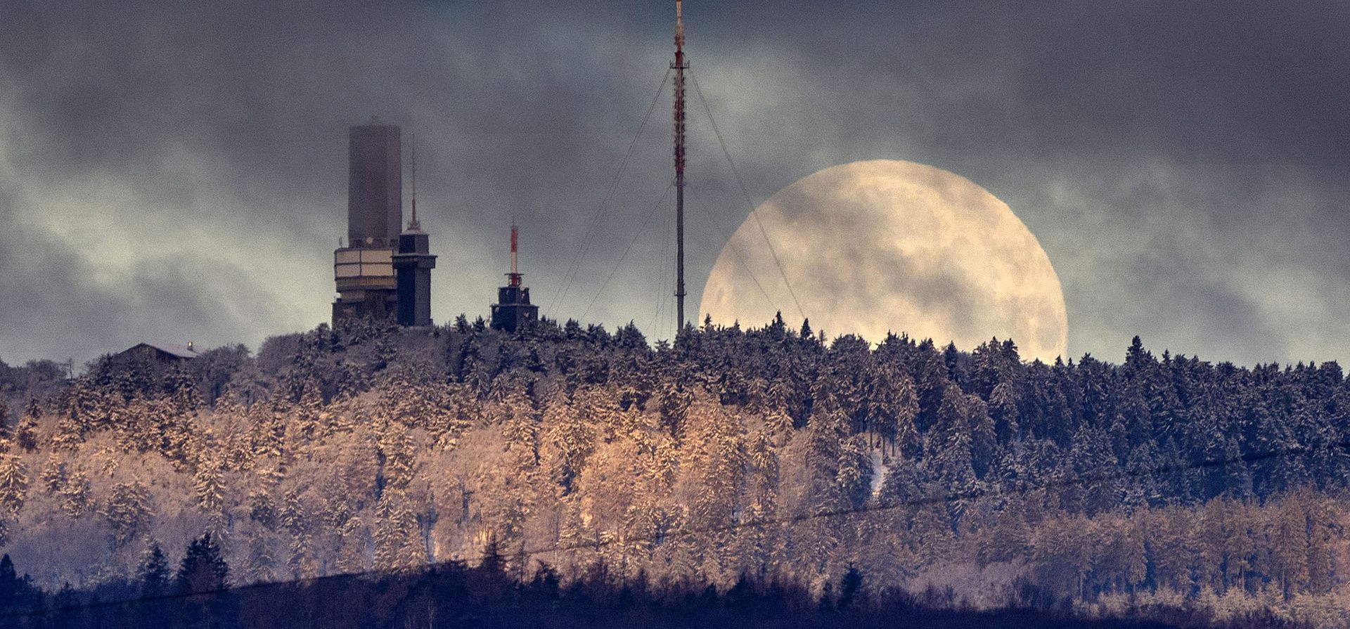 La luna se pone detrás de la cima de la montaña Feldberg cerca de Frankfurt, Alemania, la madrugada del jueves 9 de febrero de 2023. (AP Photo/Michael Probst)