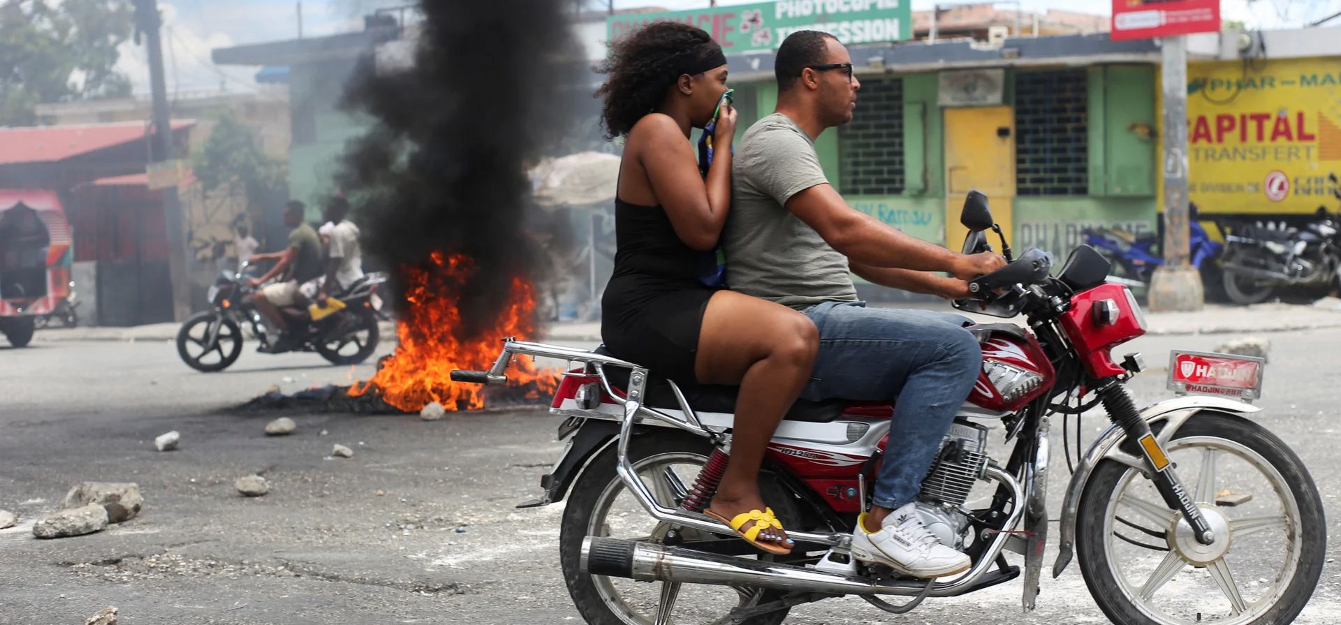Un motociclista pasa junto a una barricada en llamas durante una protesta contra la violencia relacionada con las pandillas y para exigir la renuncia del consejo presidencial de transición de Haití, Puerto Príncipe, Haití. Fotografía: Jean Feguens Regala/Reuters Un motociclista pasa junto a una barricada en llamas durante una protesta contra la violencia relacionada con las pandillas y para exigir la renuncia del consejo presidencial de transición de Haití, Puerto Príncipe, Haití. Fotografía: Jean Feguens Regala/Reuters
