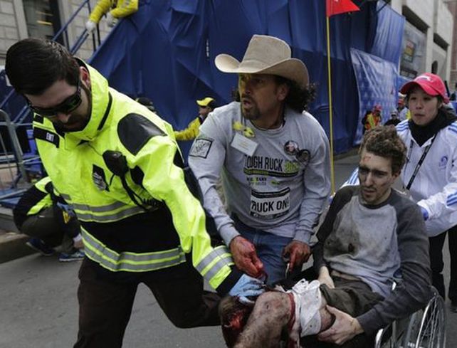 Un joven es retirado luego de resultar herido en una explosión cerca de la línea de meta del maratón de Boston.