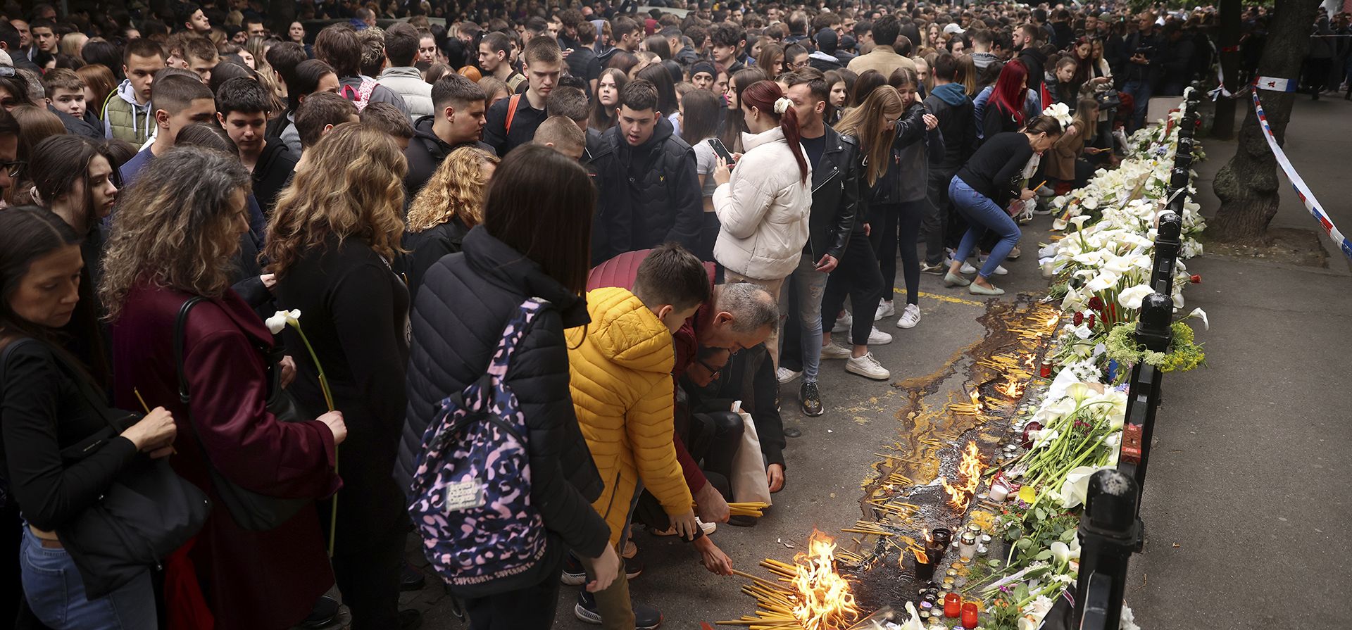 Niños en edad escolar se reúnen para encender velas por las víctimas cerca de la escuela Vladislav Ribnikar en Belgrado, Serbia, el jueves 4 de mayo de 2023. Muchos vestidos de negro y con flores, decenas de estudiantes serbios rindieron homenaje en silencio el jueves a sus compañeros asesinados el día anterior cuando un niño de 13 años usó las armas de su padre en un tiroteo en la escuela que conmocionó a todo el país y desencadenó movimientos para impulsar el control de armas. (Foto AP/Armin Durgut)