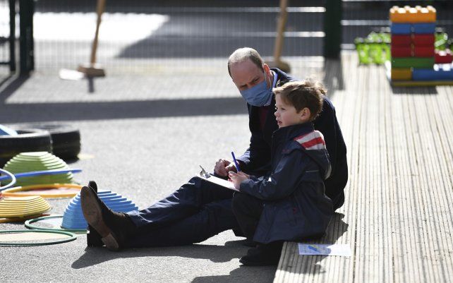El príncipe William de Gran Bretaña juega con un niño en el patio de School21, durante una visita con Kate, duquesa de Cambridge, al colegio situado en el este de Londres.