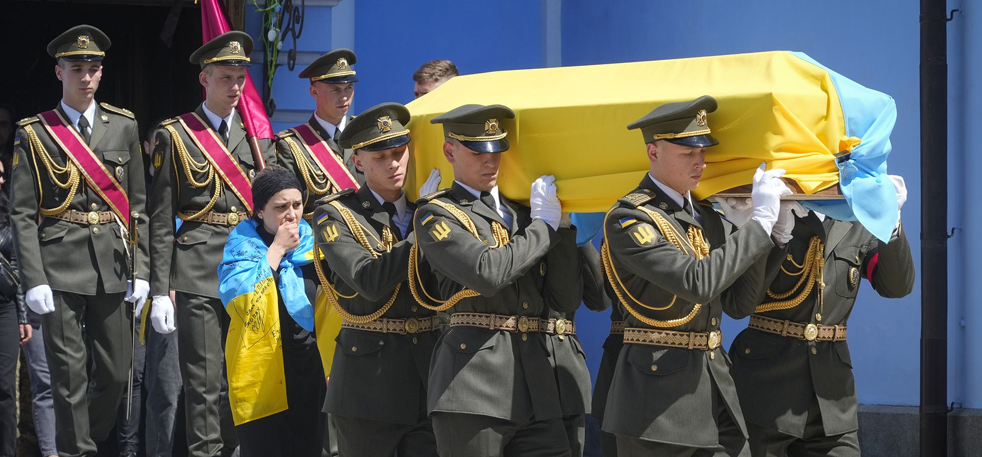 Soldados llevan un ataúd con los restos del soldado voluntario Oleksandr Makhov, un conocido periodista ucraniano, asesinado por tropas rusas, en la catedral de San Miguel en Kiev, Ucrania, el lunes 9 de mayo de 2022. El ataúd es seguido por la viuda de Makhov.