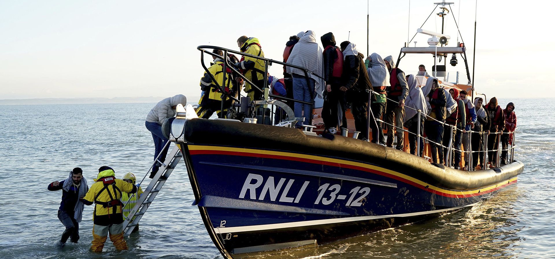 Los posibles inmigrantes, cubiertos con mantas, desembarcan de un bote después de ser rescatados en el mar cuando llegan a Dungeness, Inglaterra, el miércoles 21 de septiembre de 2022.