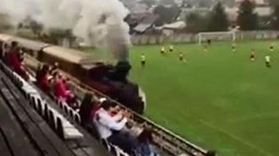 El viejo y querido trencito a vapor atraviesa una cancha de fútbol en medio de un partido