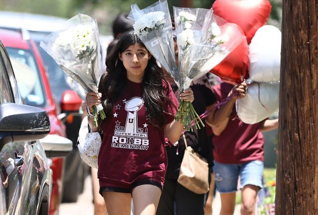 Una niña lleva flores y globos para homenajear a los alumnos muertos en Texas. (Kin Man Hui/The San Antonio Express-News via AP)