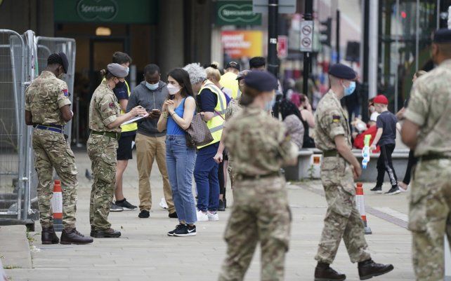Miembros de las Fuerzas Armadas hablan con personas, afuera de un centro móvil de vacunación COVID-19 fuera del Ayuntamiento de Bolton, Inglaterra, donde los números de casos de la variante Delta identificados por primera vez en India han sido relativamente altos. 