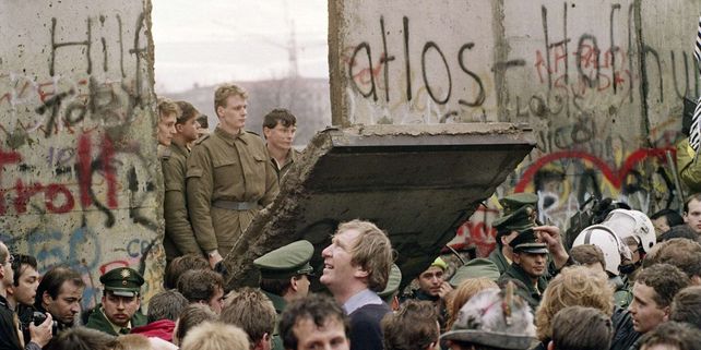 Soldados del este miran a través del muro tras ser retirado un bloque.