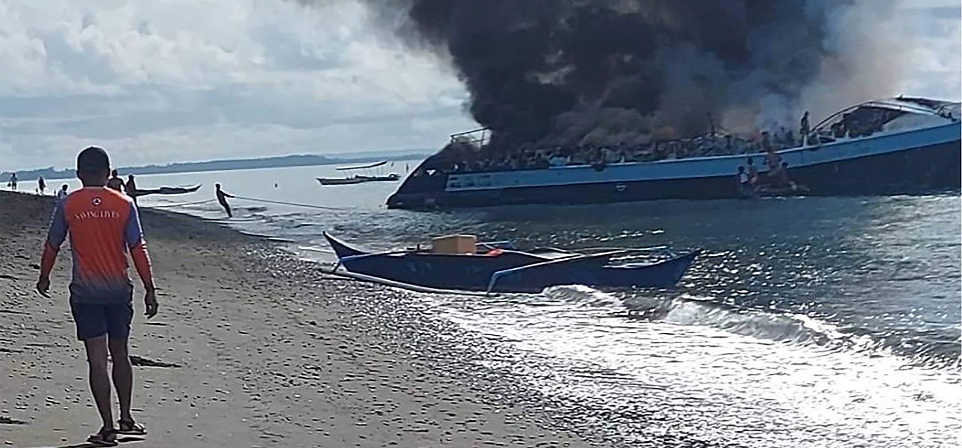 El humo sale del ferry M/V Mercraft 2 cuando es remolcado a una isla frente a la ciudad de Real, provincia de Quezon, Filipinas, el lunes 23 de mayo de 2022. El barco de pasajeros se incendió cuando se acercó a su destino portuario en Real, se reportó un numero de personas fallecidas a bordo.
