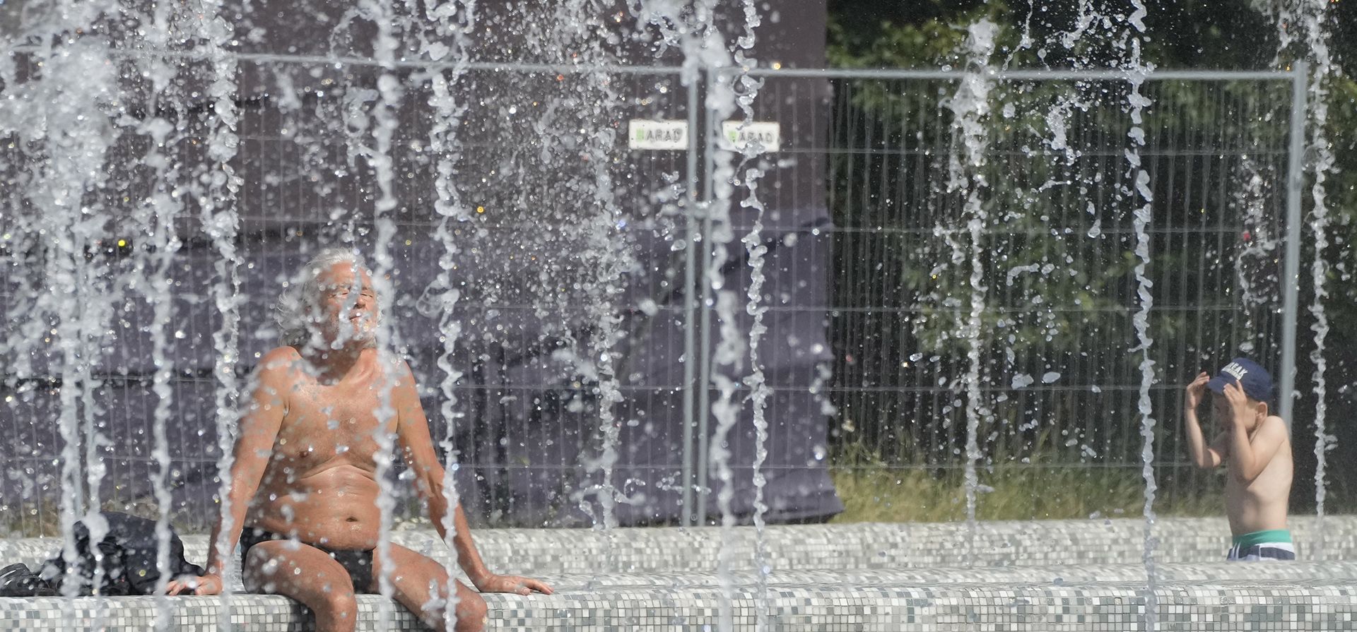 La gente se refresca junto a las fuentes en un clima cálido que alcanza los 35º grados en Varsovia, Polonia. (AP Photo/Czarek Sokolowski)