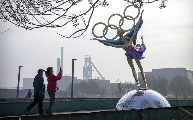 Turistas toman fotos de una estatua de patinadores artísticos con los anillos olímpicos en un parque cerca de la sede del Comité Organizador de los Juegos Olímpicos de Beijing (BOCOG) en Beijing