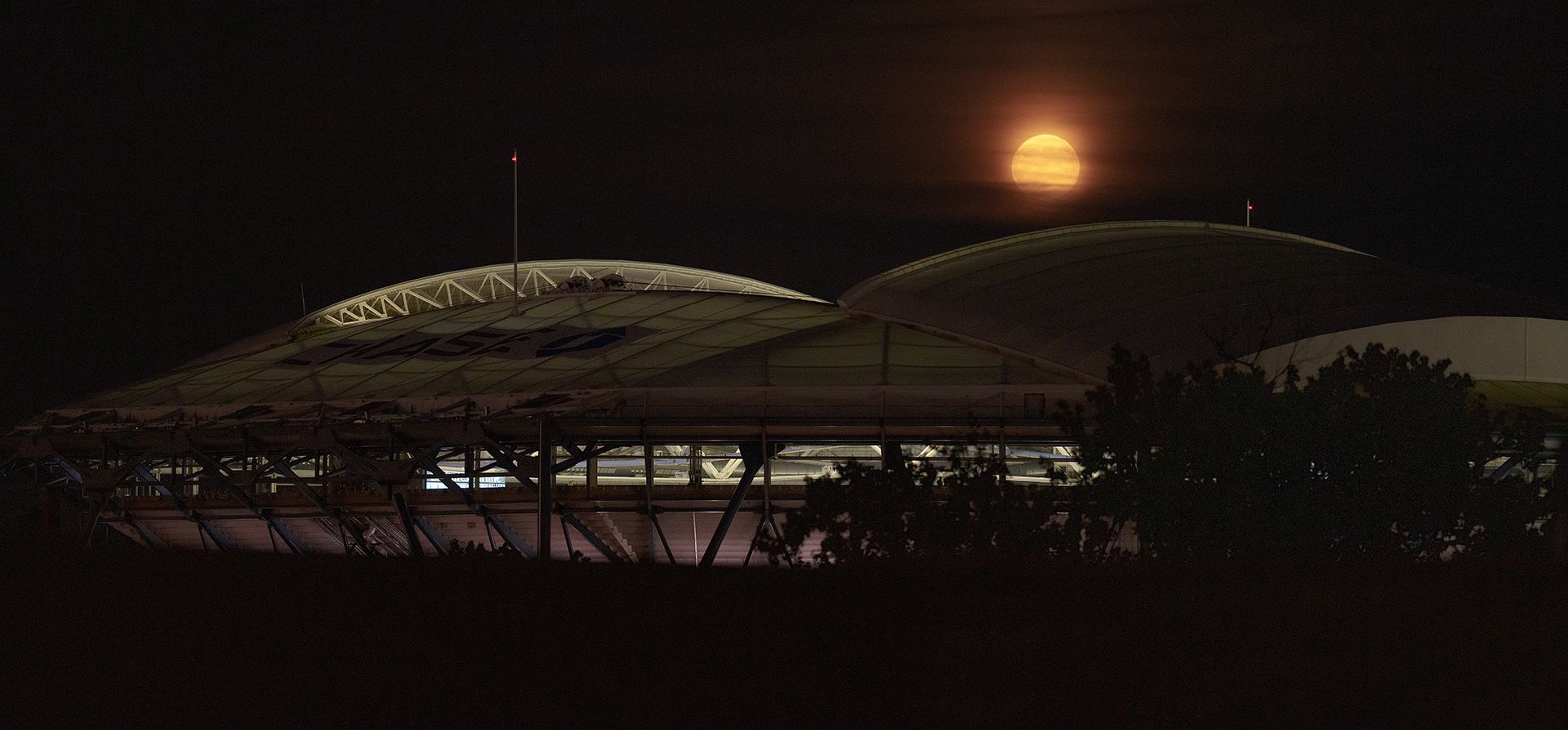 Una superluna se eleva detrás del estadio Arthur Ashe en el Centro Nacional de Tenis Billie Jean King durante la segunda ronda del campeonato de tenis del Abierto de Estados Unidos, el miércoles 30 de agosto de 2023, en Nueva York. (Foto AP/Manu Fernández)