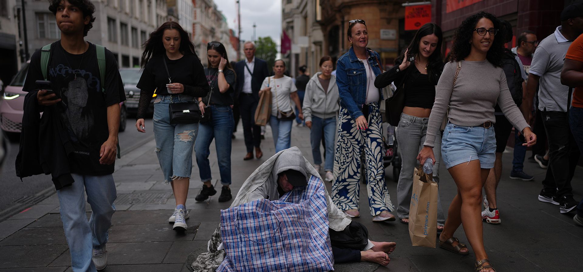 Un hombre sin hogar se sienta en una calle de una zona comercial del centro de Londres, el miércoles 19 de agosto de 2026. (Foto AP/Kin Cheung)