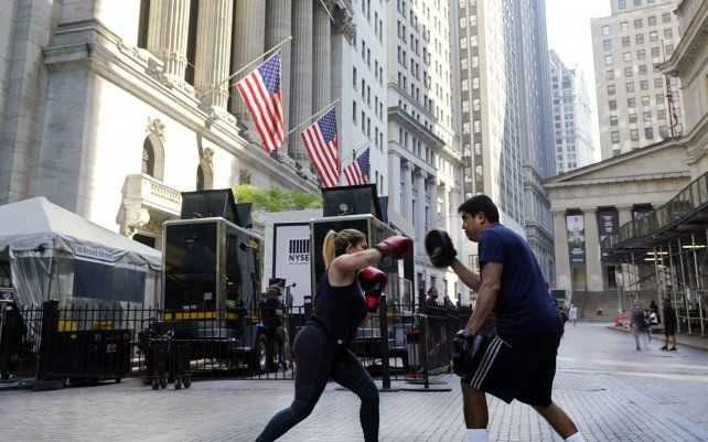 Una mujer y su personal trainer entrenan fuera de la Bolsa de Valores de Nueva York. Las acciones están subiendo mayormente en las primeras operaciones, colocando al S&P 500 y al Promedio Industrial Dow Jones cerca de los máximos históricos que alcanzaron hace un mes.