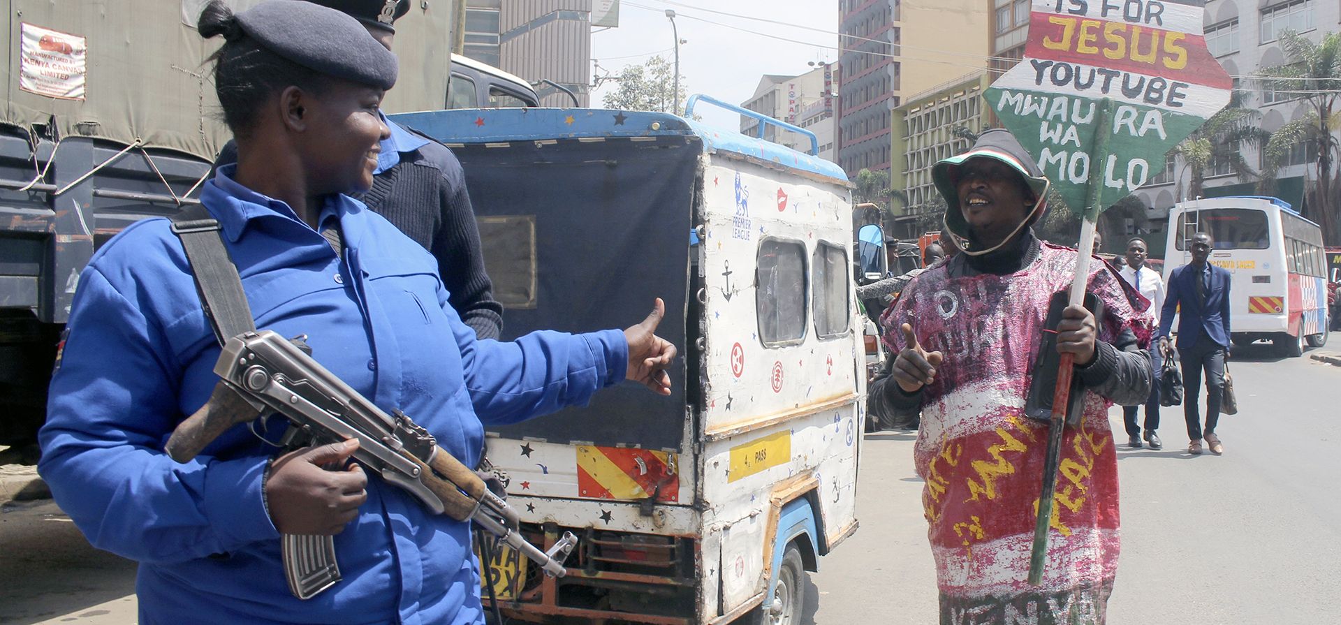 Un hombre que lleva un saco con mensajes de paz y un cartel que dice "Predica la paz" habla con un oficial de policía que patrulla las calles en Nairobi, Kenia, el 16 de agosto de 2022, después de que William Ruto fuera declarado el lunes quinto presidente de Kenia por la Comisión Electoral.
