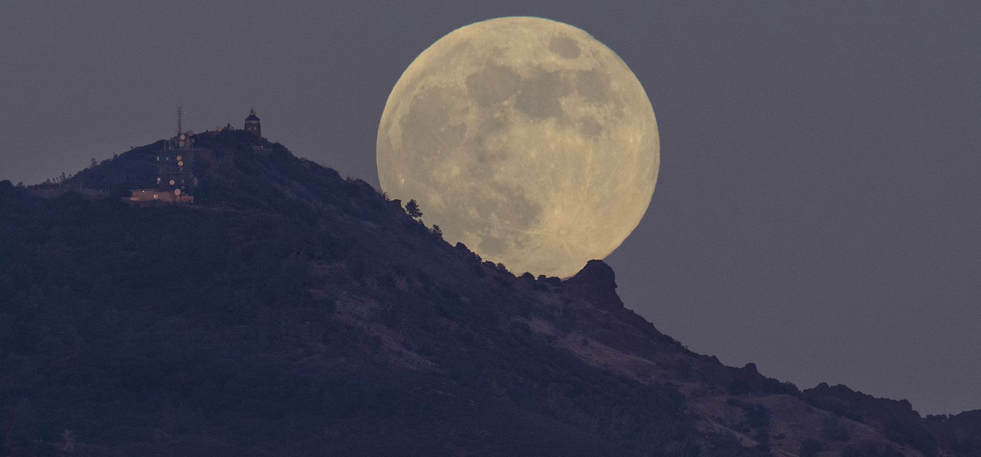 Un vehículo sube a la montaña mientras la luna llena se eleva cerca de la cima del Monte Diablo antes de que se encienda la baliza, fotografiada desde Moraga, California, el miércoles 7 de diciembre de 2022. (José Carlos Fajardo/Bay Area News Group vía AP)