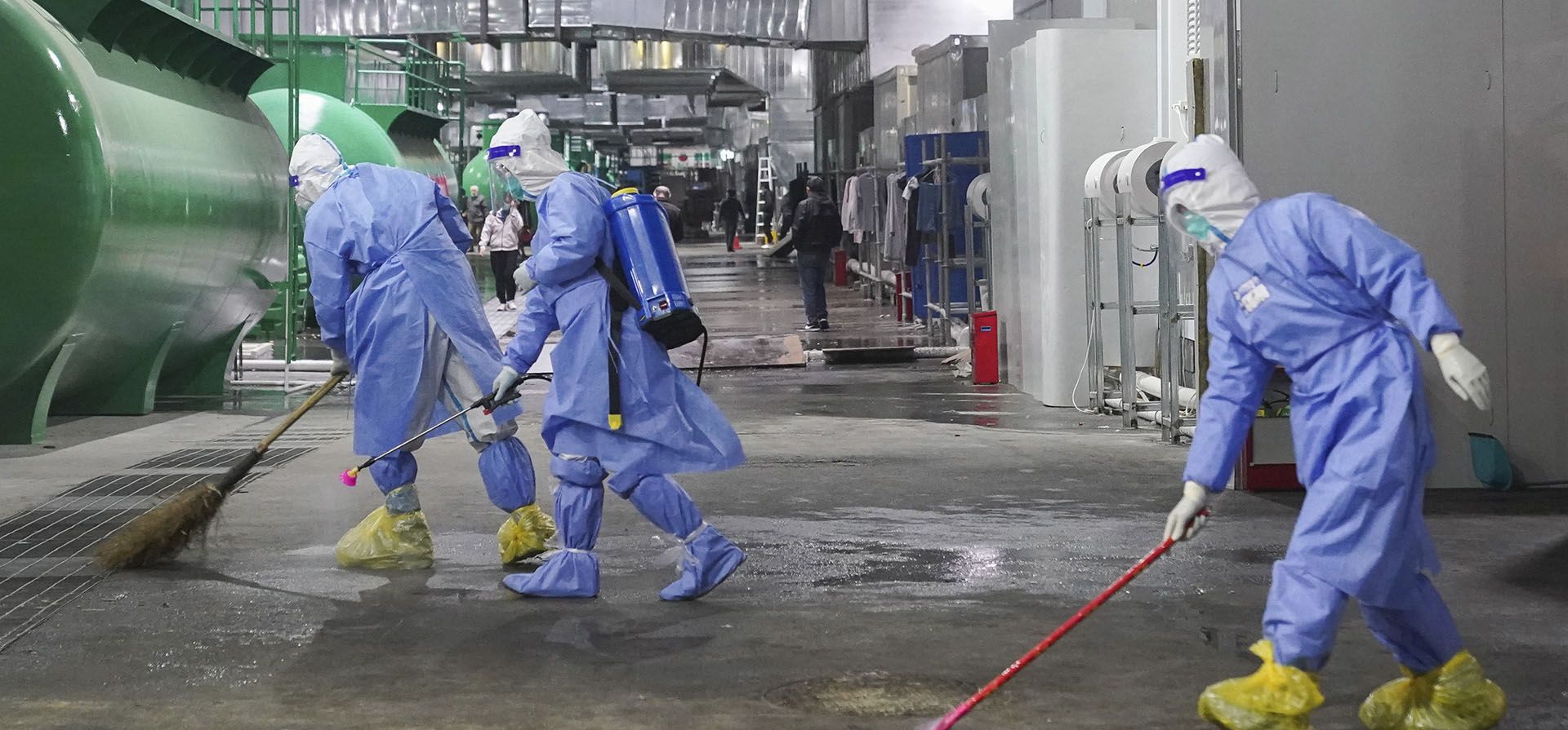 Trabajadores limpian y desinfectan el piso de un hospital improvisado en el Centro Nacional de Exposiciones y Convenciones en Shanghái, el jueves 14 de abril de 2022. Los controles antivirus que cierran algunas de las ciudades más grandes de China.